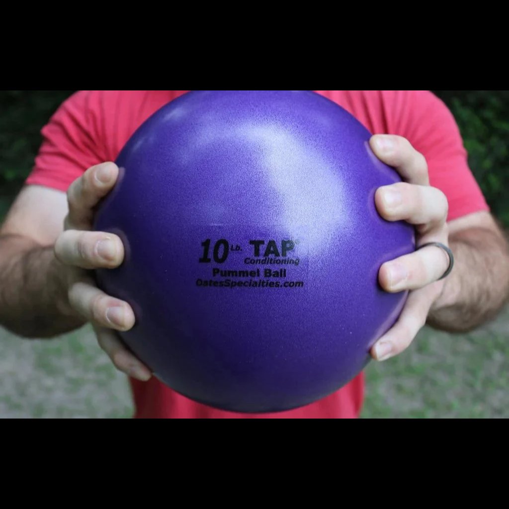 An athlete grips a purple 10lb pummel ball with two hands showing the size and the textured finish.