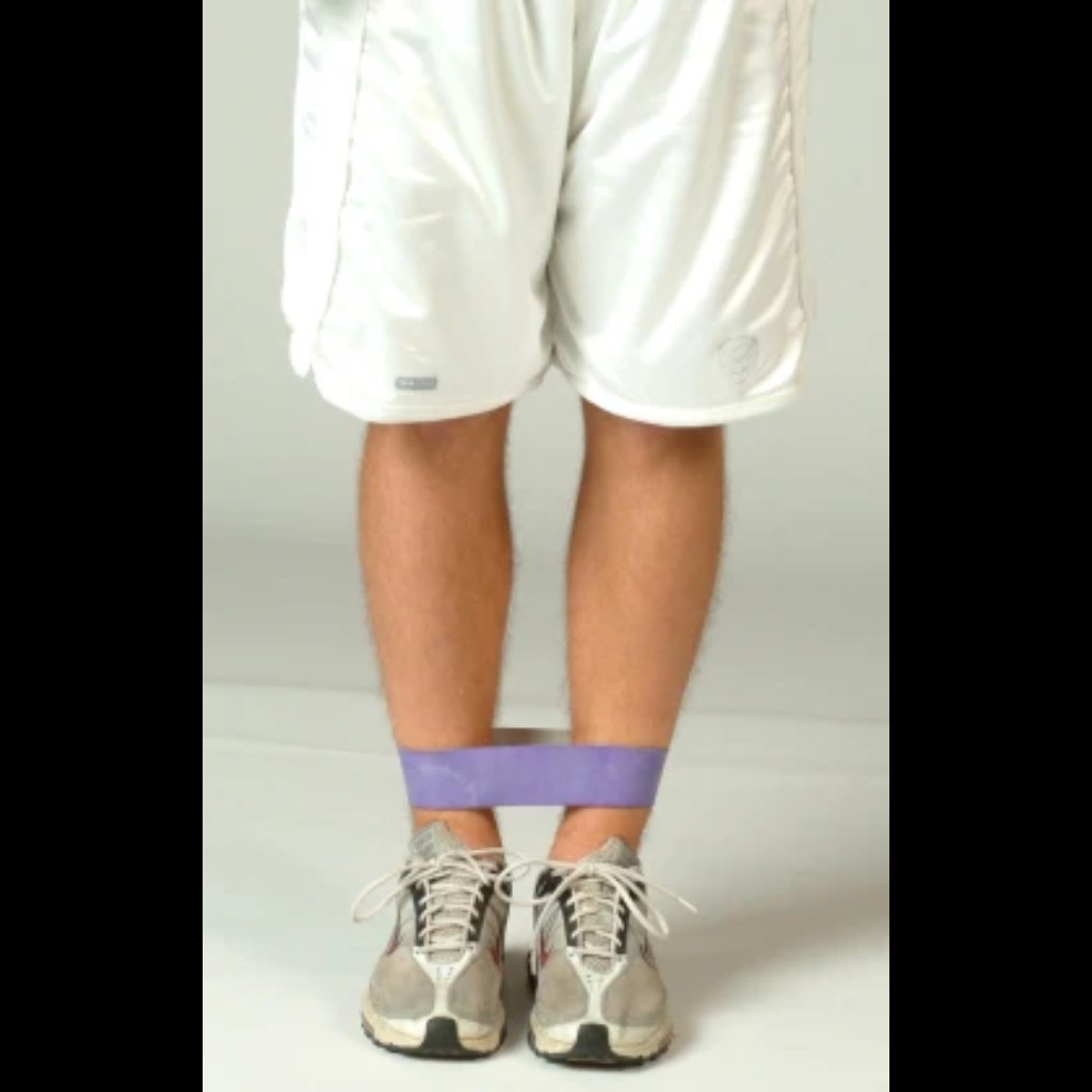 Athlete seated or lying down with a resistance band wrapped snugly around closed legs, emphasizing inner thigh engagement and controlled isometric tension.