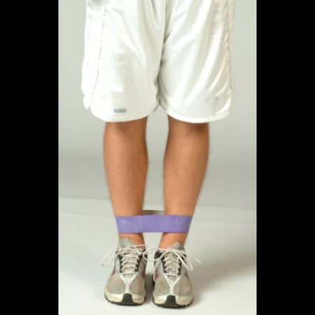 Athlete seated or lying down with a resistance band wrapped snugly around closed legs, emphasizing inner thigh engagement and controlled isometric tension.