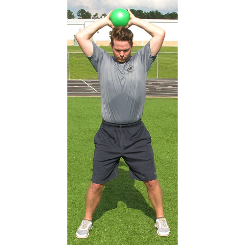 Athlete raises a green pummel ball overhead with both hands, poised for a powerful slam.