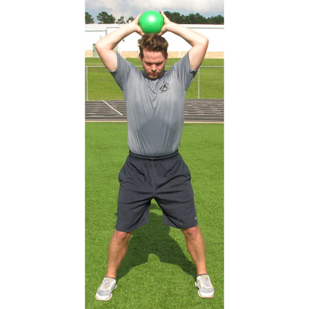 Athlete raises a green pummel ball overhead with both hands, poised for a powerful slam.