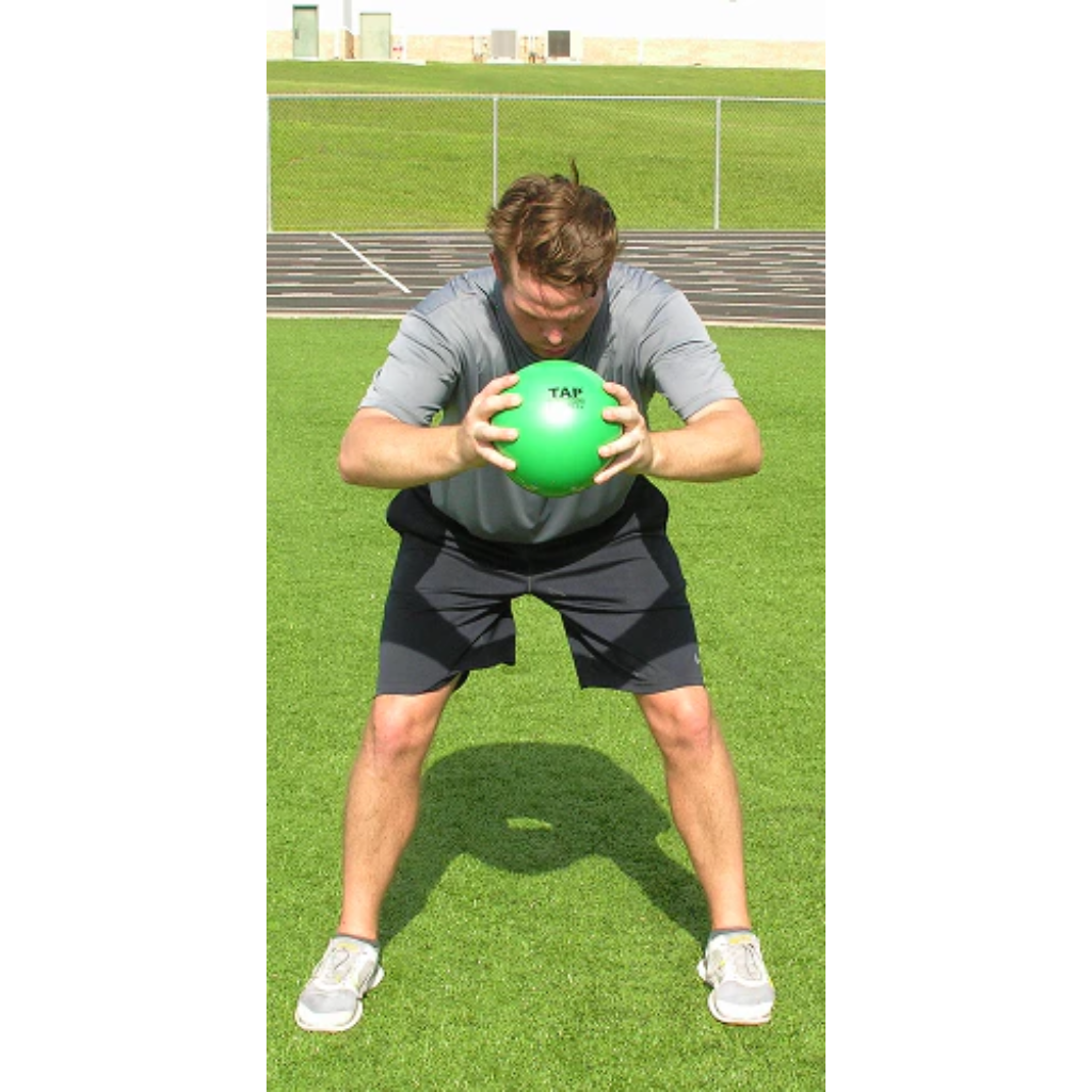 Athlete in a bent-over position slams a green pummel ball to the ground with both hands, generating powerful impact.