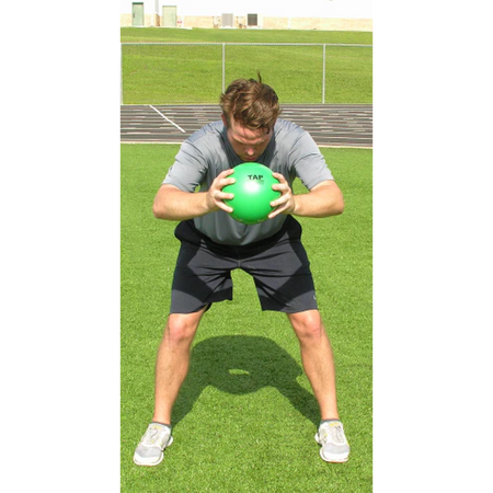 Athlete in a bent-over position slams a green pummel ball to the ground with both hands, generating powerful impact.