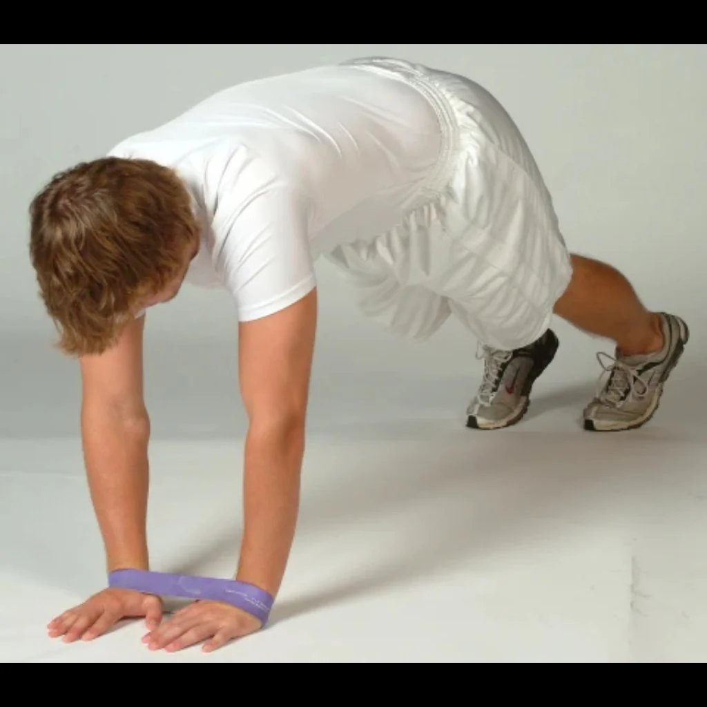 Athlete performing a diamond push-up with a resistance band looped around the wrists, emphasizing triceps activation, shoulder stability, and added upper body tension.