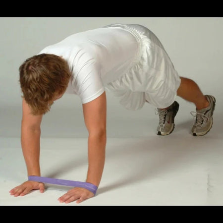 Athlete in a push-up stance with a resistance band looped around the wrists, emphasizing shoulder stability and upper body activation.