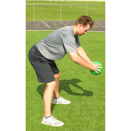 Athlete holding a green pummel ball at knee level, just before releasing it for a ground slam.