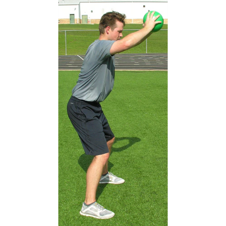 Athlete gripping a green pummel ball at eye level with both hands, slamming it to the ground.