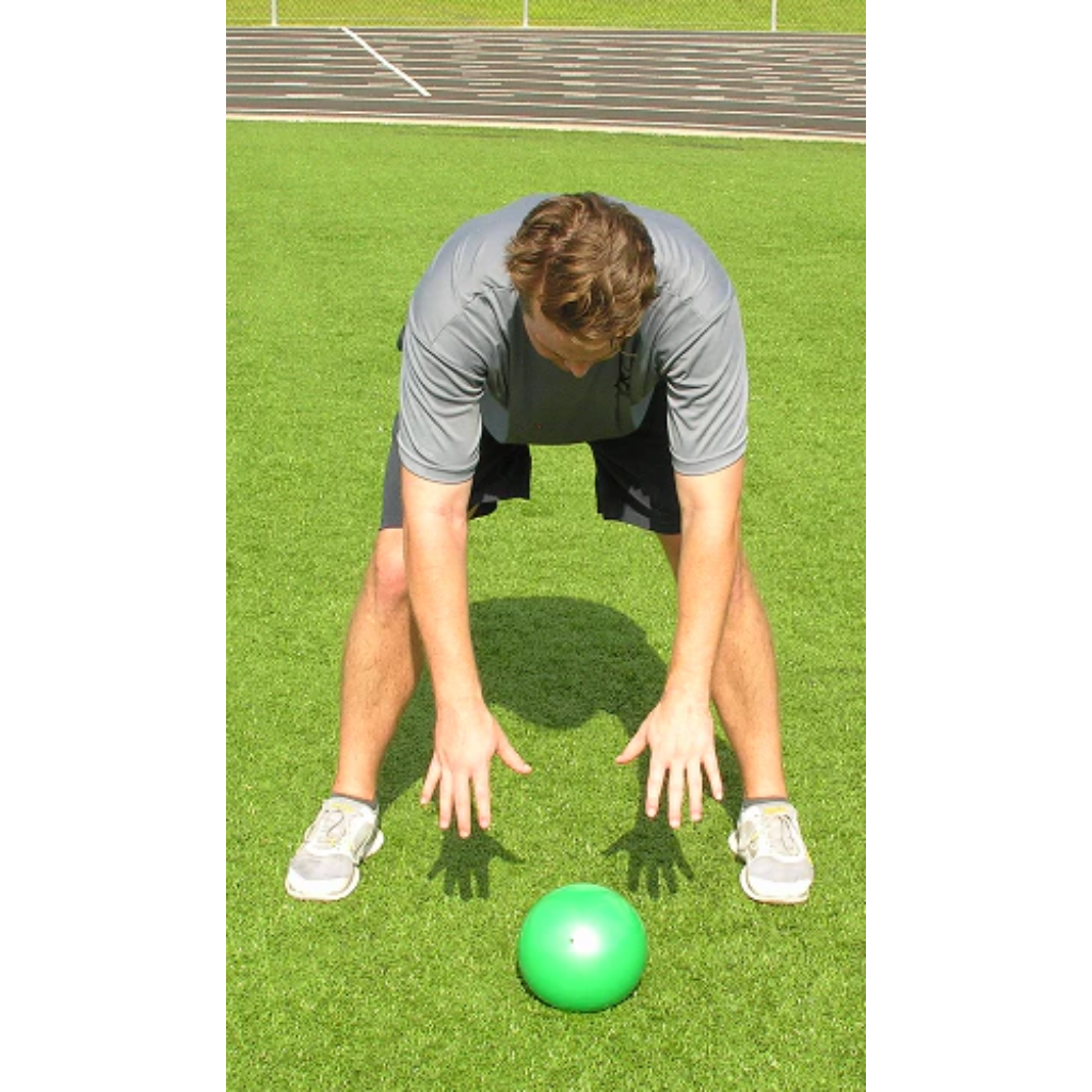 Athlete completes a slam, with the green pummel ball resting on the ground after impact.