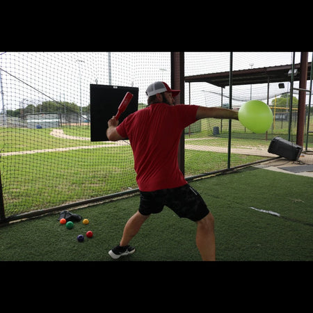 Connector Throwing Club being held in one hand, and the Connection Ball in the other hand. The athlete is rearing back to make a throw.
