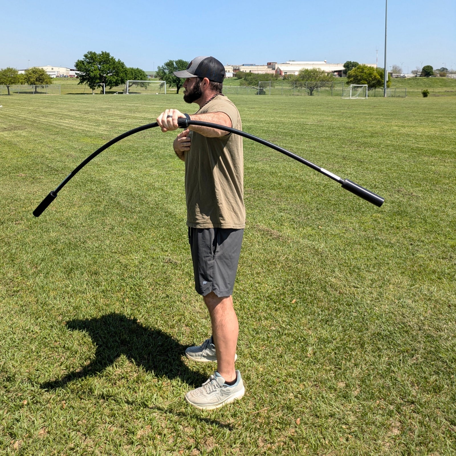 An athlete grips the TAP® Shoulder Tube with palms facing down, moving it vertically to generate oscillations. The controlled resistance engages and strengthens the arm and shoulder complex, making it an effective dynamic warm-up tool.