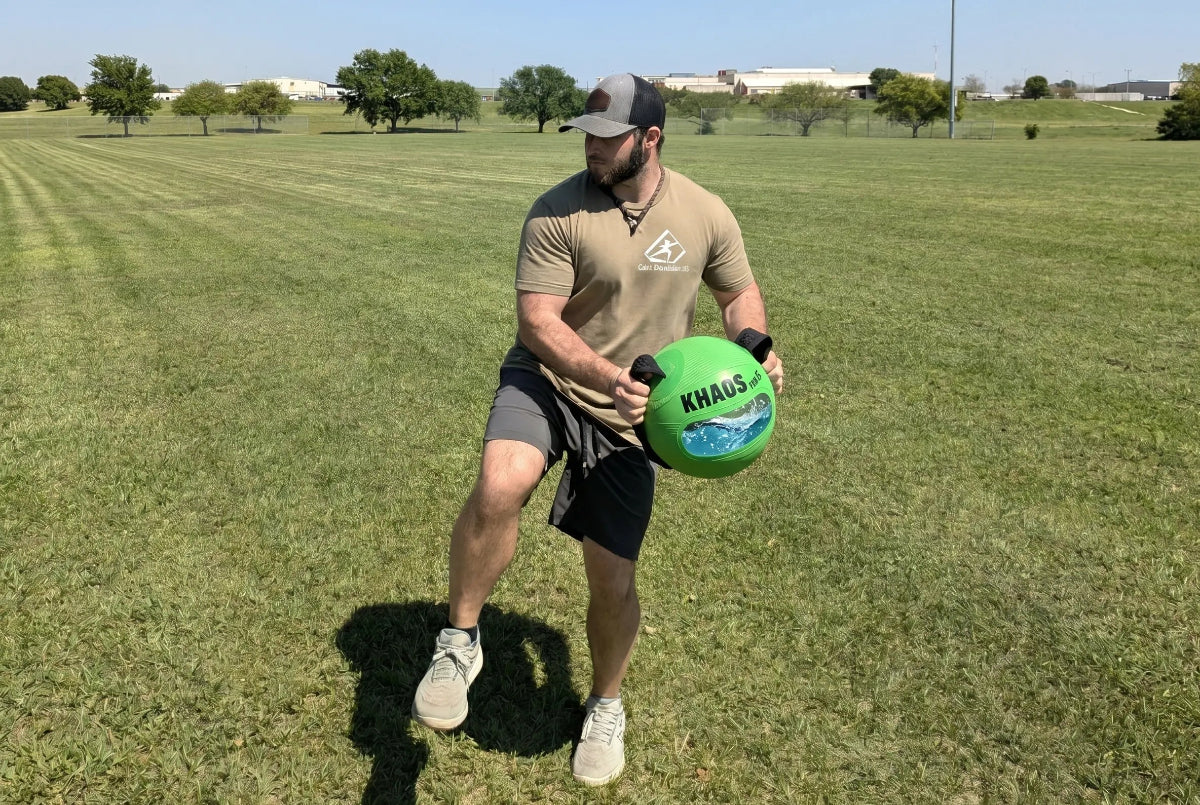 Athlete loading back hip tension to activate the kinetic chain with the unstable load caused by water shifting inside the KHAOS® Water Ball.