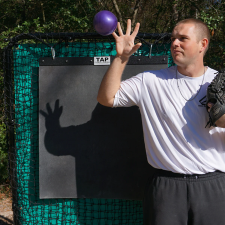 A TAP® Mini-Medicine Ball in the air, captured at the peak of a toss during a training exercise.