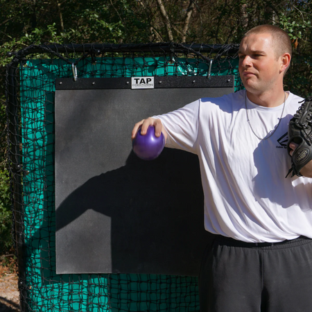 Athlete grips a 4lb TAP® Mini-Medicine Ball, preparing to perform a reverse throw exercise to strengthen arm decelerators.