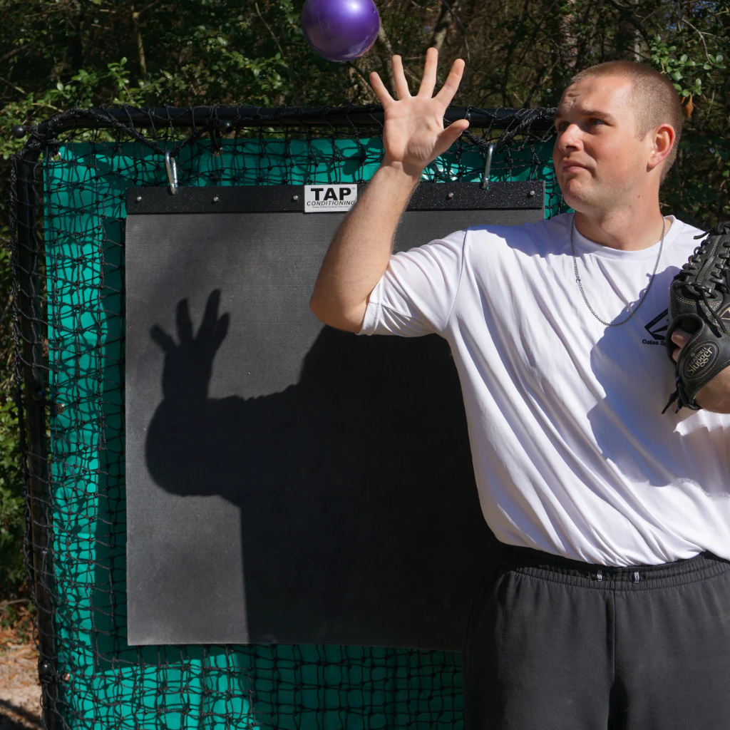 A TAP® Mini-Medicine Ball suspended in mid-air, about to be caught by an athlete during a training drill.