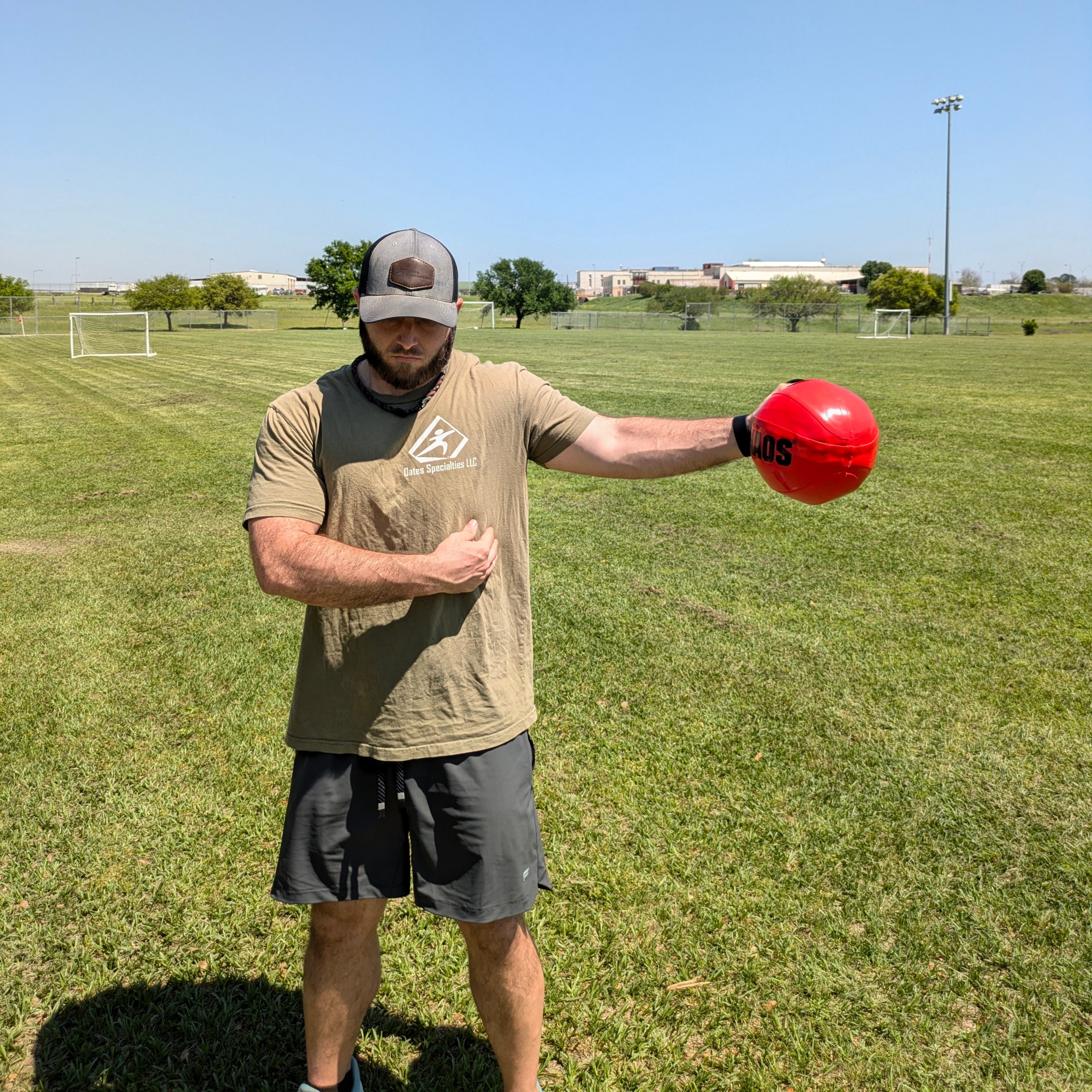 Front view of an athlete using a water-filled mini aqua at their side for a dynamic shoulder warm-up and arm strengthening routine. See how perturbation training activates the shoulder complex.