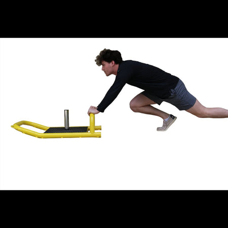 Young athlete pushing a resistance sled across turf to build lower body strength, power, and athletic performance.