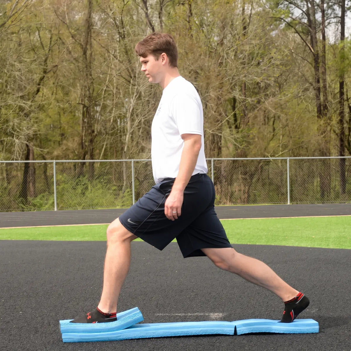 Athlete performing a lunge on a partially folded Folding Balance Beam, utilizing an asymmetrical unstable variable stimulus for lead-side stabilization and kinetic chain organization.