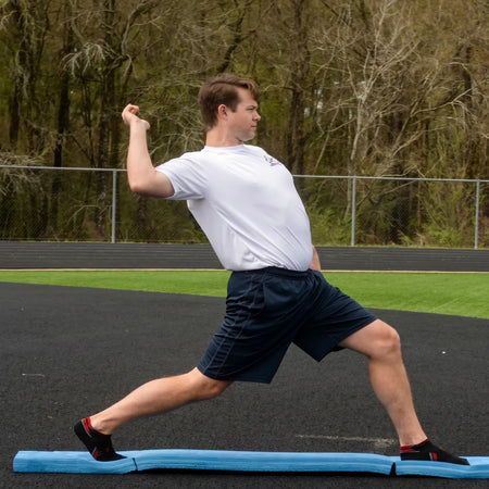 Athlete performing the arm layback phase on the Folding Balance Beam, utilizing a narrowed unstable variable stimulus for lead-side stabilization and kinetic chain organization.