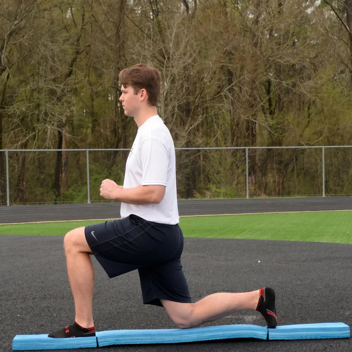 Athlete performing a lunge on the Folding Balance Beam, utilizing a narrowed unstable variable stimulus for lead-side stabilization and kinetic chain organization.