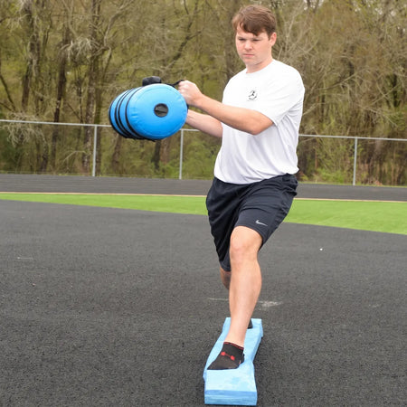 Athlete performing a lunge and trunk twist with a Blue Waterboy on the Folding Balance Beam, utilizing compounded unstable variable stimuli for lead-side stabilization and kinetic chain organization.
