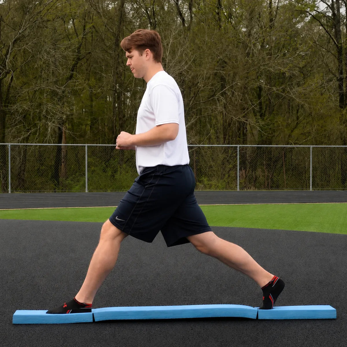 Athlete performing a standing split on the Folding Balance Beam, utilizing a narrowed unstable variable stimulus for lead-side stabilization and kinetic chain organization.