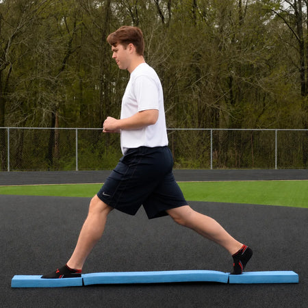 Athlete performing a standing split on the Folding Balance Beam, utilizing a narrowed unstable variable stimulus for lead-side stabilization and kinetic chain organization.