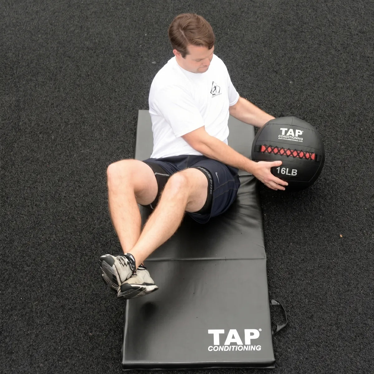 Athlete using 16lb soft medicine ball in Russian twist for core stability.