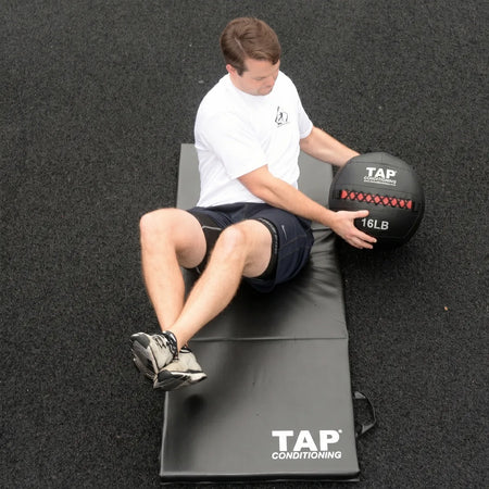 Athlete using 16lb soft medicine ball in Russian twist for core stability.
