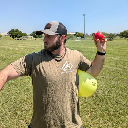 Athlete using the TAP® Connection Ball® as a tactile constraint below the shoulder to support consistent torso-arm connection and efficient sequencing during the throwing motion.