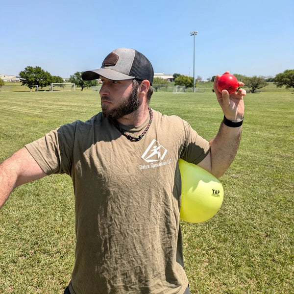 Athlete using the TAP® Connection Ball® as a tactile constraint below the shoulder to support consistent torso-arm connection and efficient sequencing during the throwing motion.
