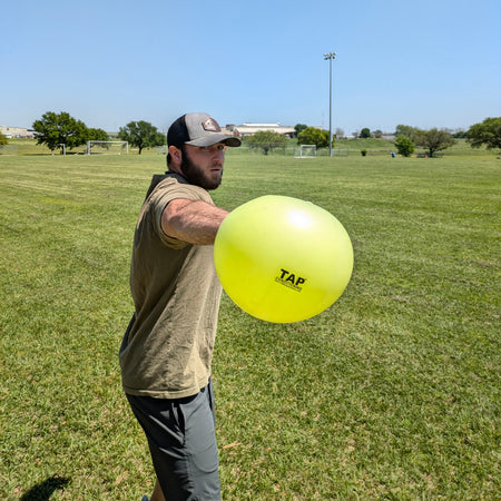 An athlete gripping the TAP® Connection Ball with the glove side hand to help the athlete feel what an efficient glove side movement pattern feels like.