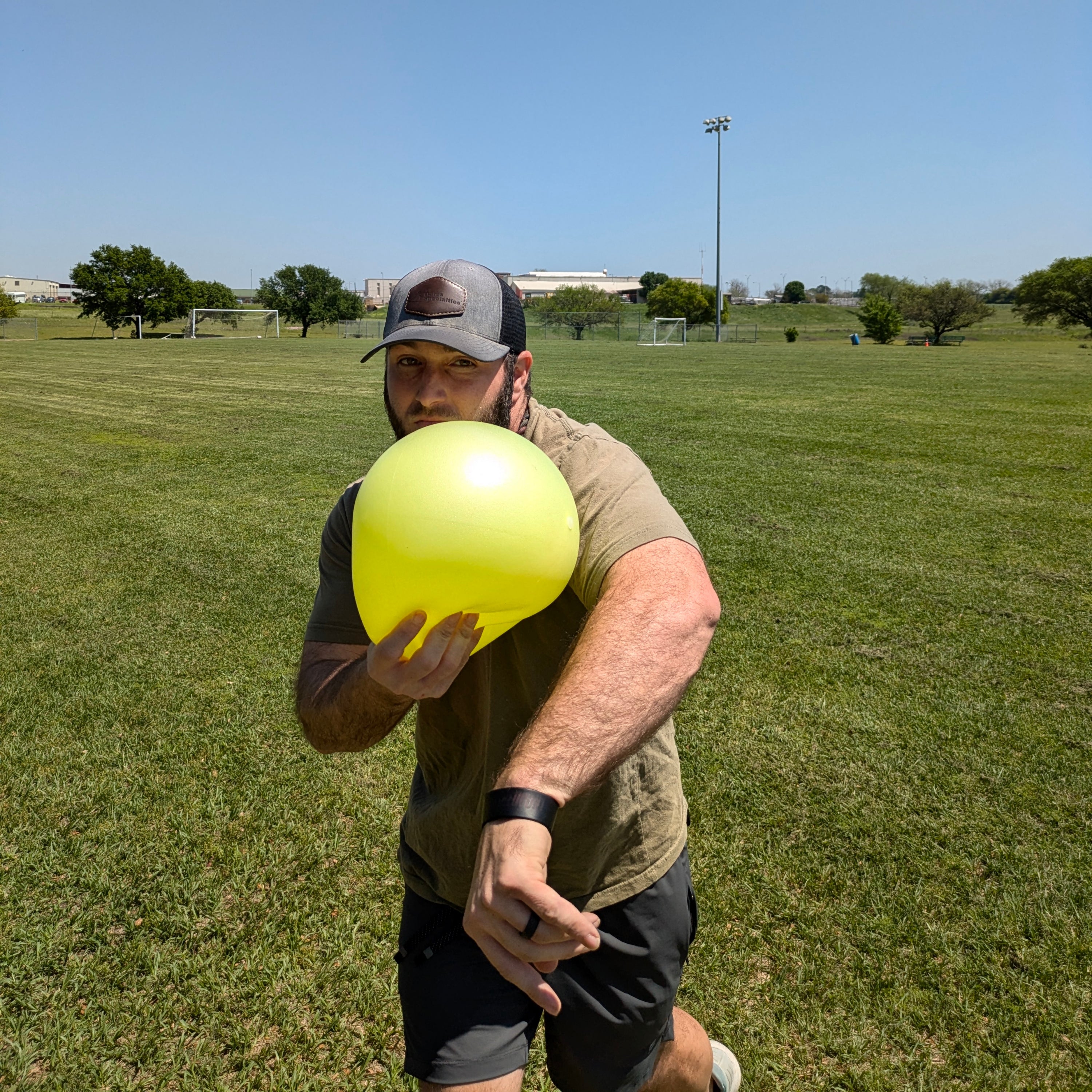 An athlete grasps the TAP® Connection Ball in the glove side hand. The athlete has released the baseball, and the body has rotated to the glove side with the Connection Ball. The Connection Ball is on the athlete's cheek symbolizing efficient glove side patterns.