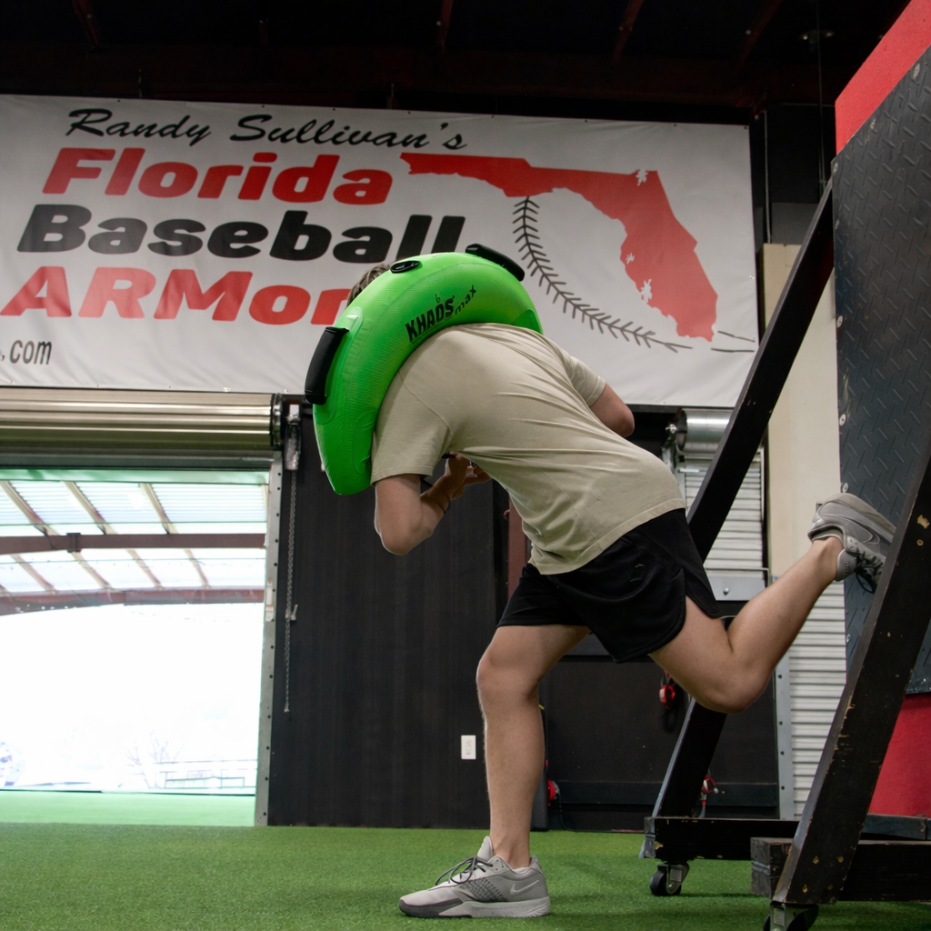 Athlete at Florida Baseball ARMory using the Khaos Bulgarian Water Bag for focused core and leg stabilization training. Bracing against a wall enhances targeted muscle engagement for improved pitching performance.