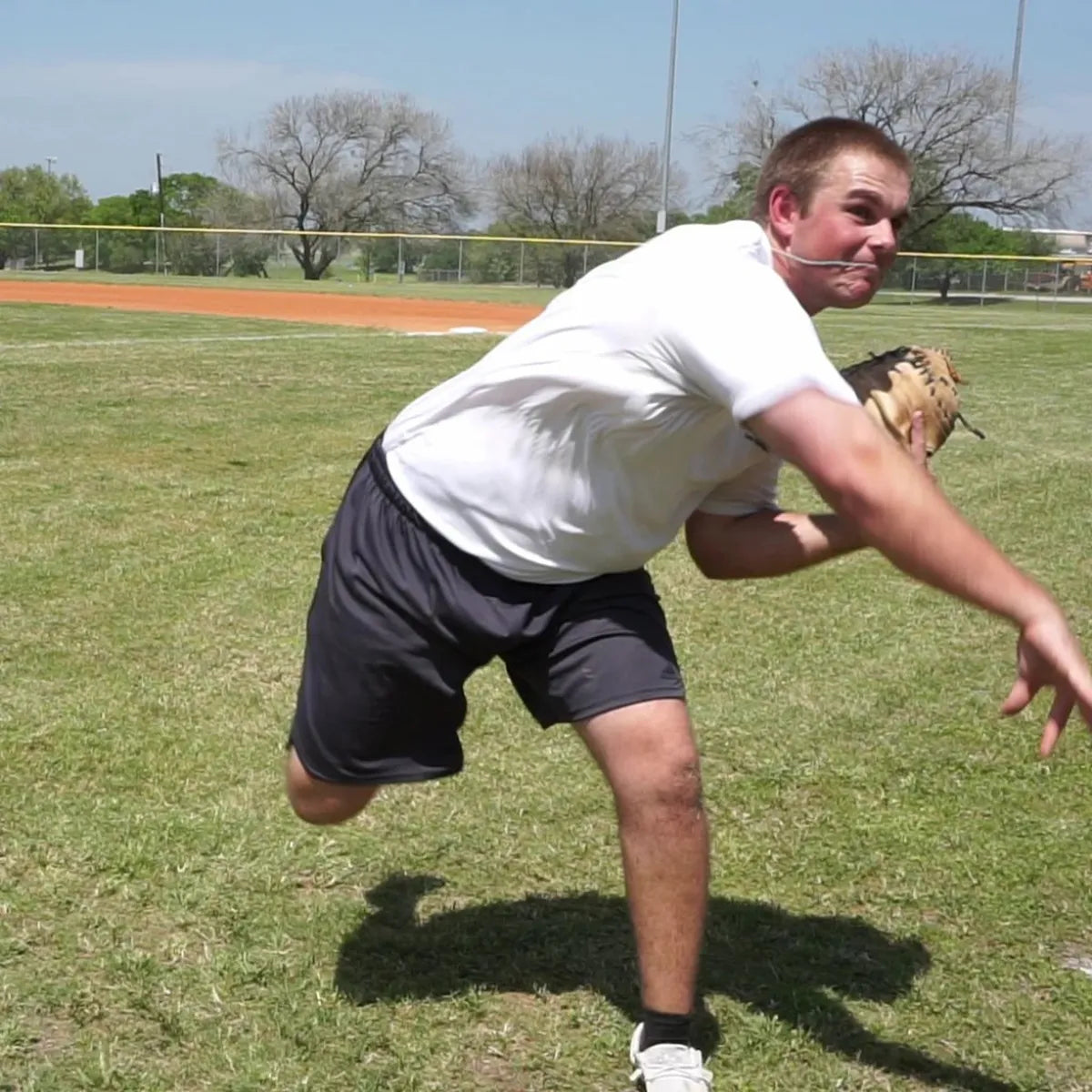 Catcher completing the follow-through with a DTS weighted training ball, utilizing a variable-load stimulus to drive kinetic chain organization and maximize force transmission through the throwing arm.
