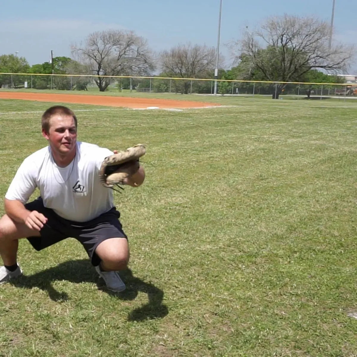 Catcher receiving a pitch with a DTS weighted training ball, utilizing a variable-load stimulus to drive scapular stabilization and kinetic chain organization for increased power.