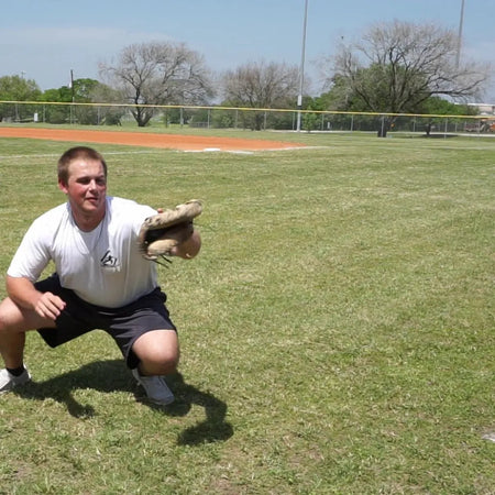 Catcher receiving a pitch with a DTS weighted training ball, utilizing a variable-load stimulus to drive scapular stabilization and kinetic chain organization for increased power.