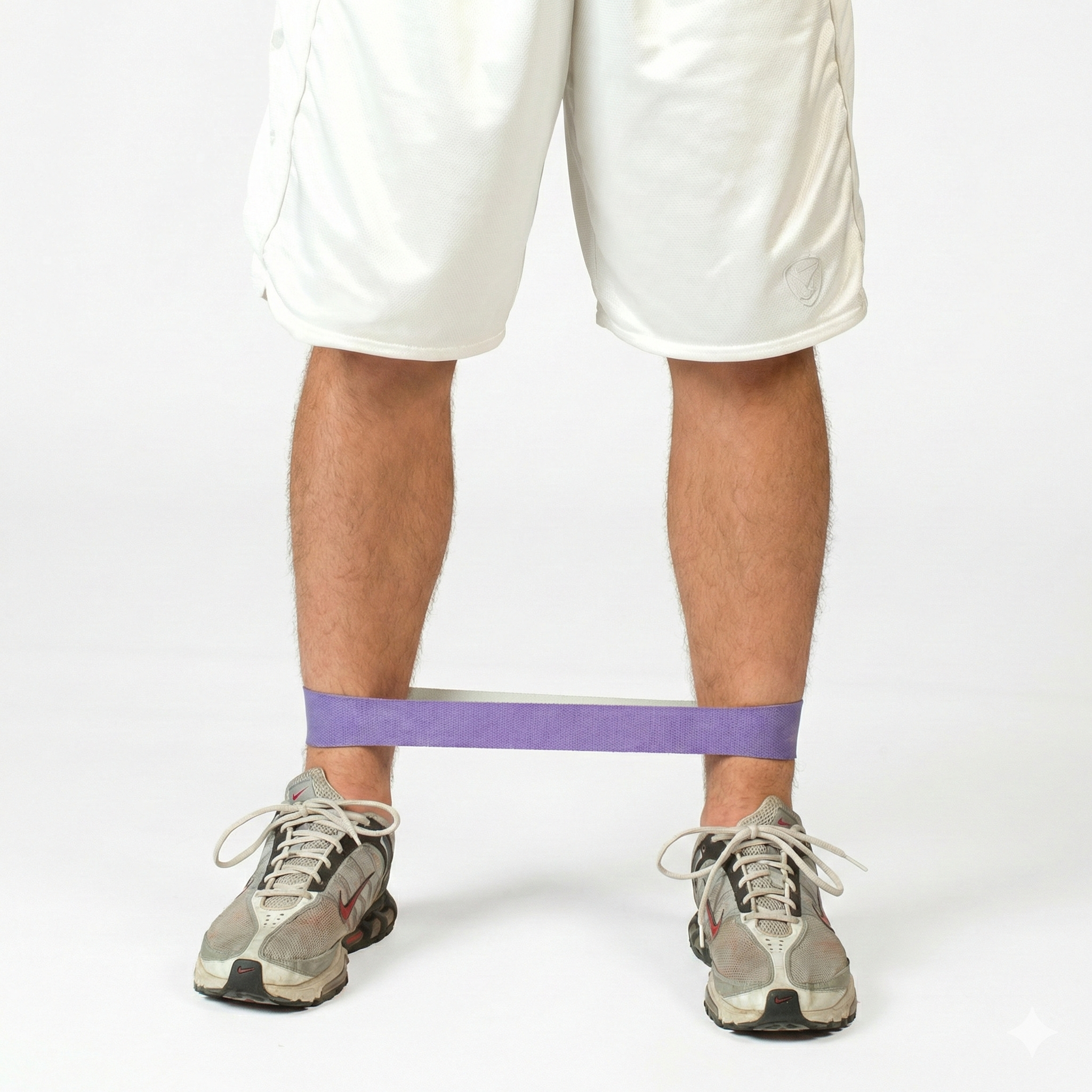 Athlete performing resisted lateral walks with a TAP® Exercise Band around the ankles to prioritize hip abductor activation and maintain pelvic control through multi-planar movement.
