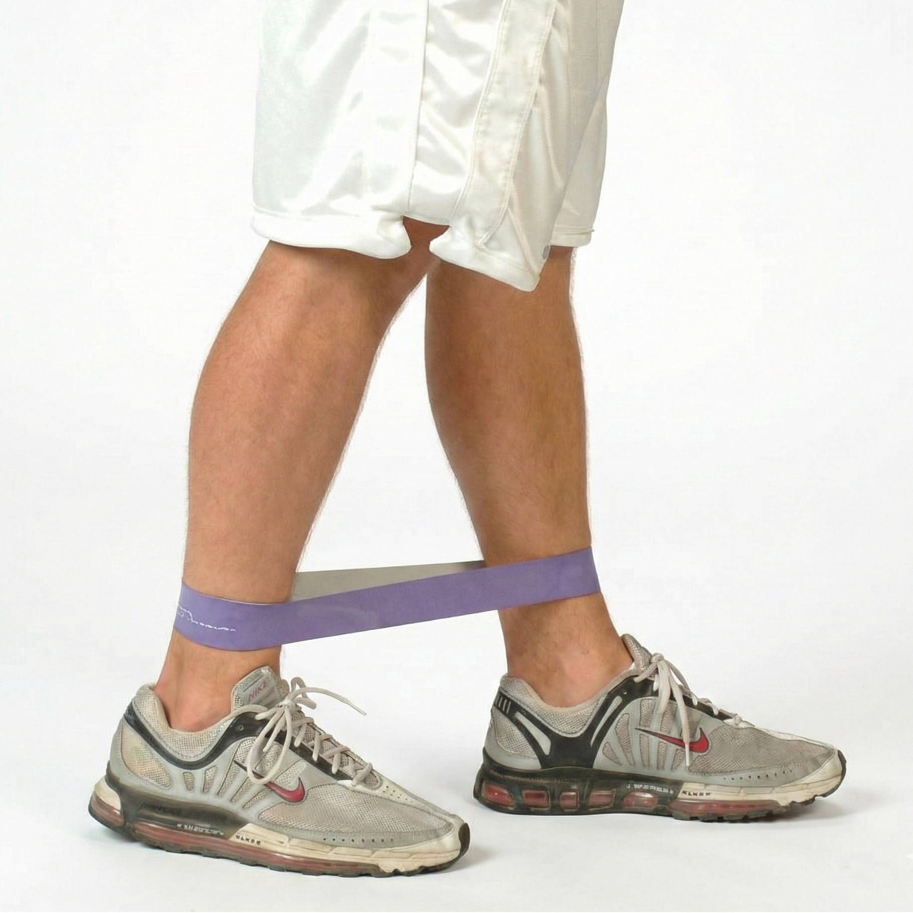 Athlete performing resisted lateral walks with a TAP® Exercise Band around the ankles to prioritize hip abductor activation and maintain pelvic control through multi-planar movement.