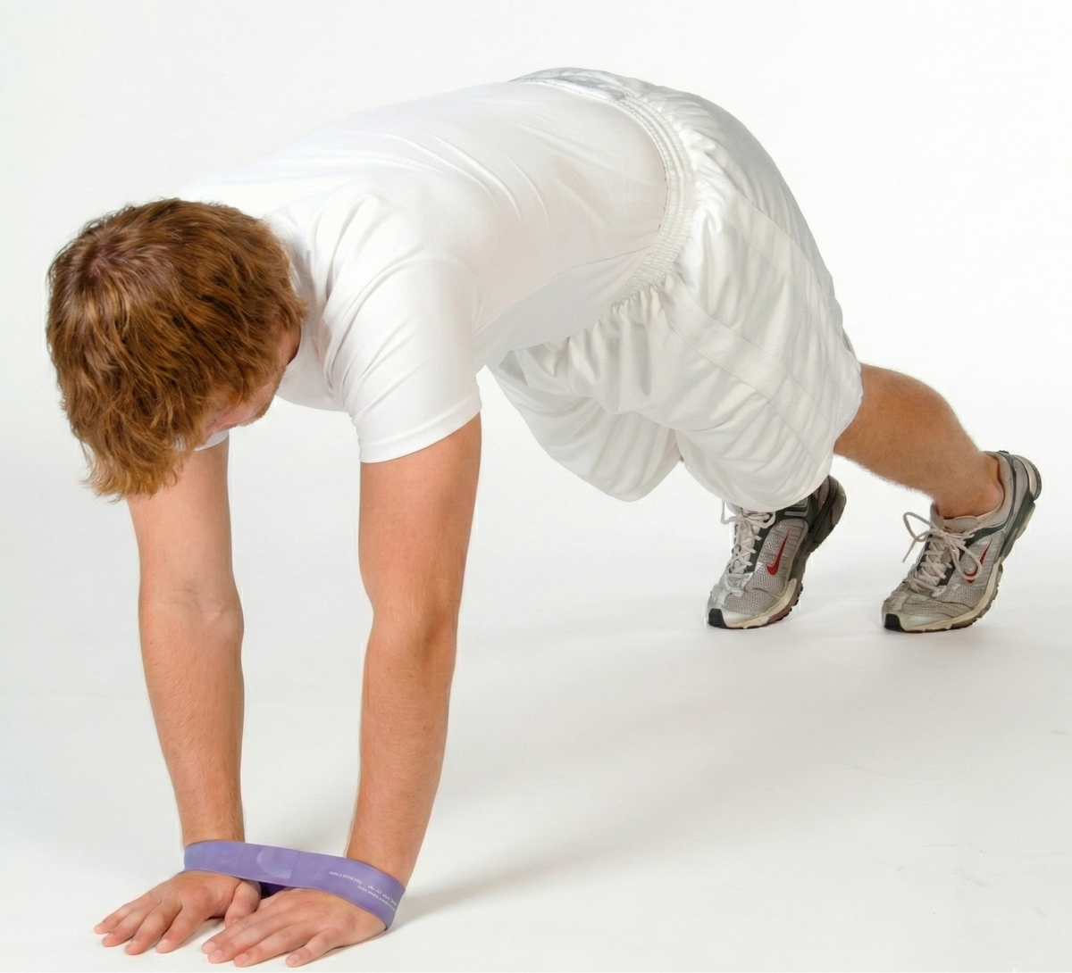 Athlete performing a diamond push-up with a TAP® Exercise Band around the wrists to facilitate high-tension triceps activation and reinforce shoulder complex stability through the entire movement arc.