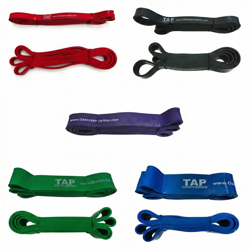 A developmental grid of five TAP® Giant Flat Bands organized by resistance profile. The Red (top left) and Black (top right) 1/2" bands represent foundational movement tools for rhythmic patterning. Centered is the Purple band for intermediate loading. The Bottom Left features the Green band for collegiate-level force output, while the Bottom Right displays the Blue band, specifically engineered for the specialized structural stability requirements of very mature, muscular athletes.