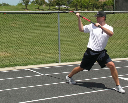 Athlete performing an over-the-shoulder wood chopper with the KHAOS Pivoter, utilizing elastic rhythmic perturbations to drive lead-side stabilization and kinetic chain organization for increased power.