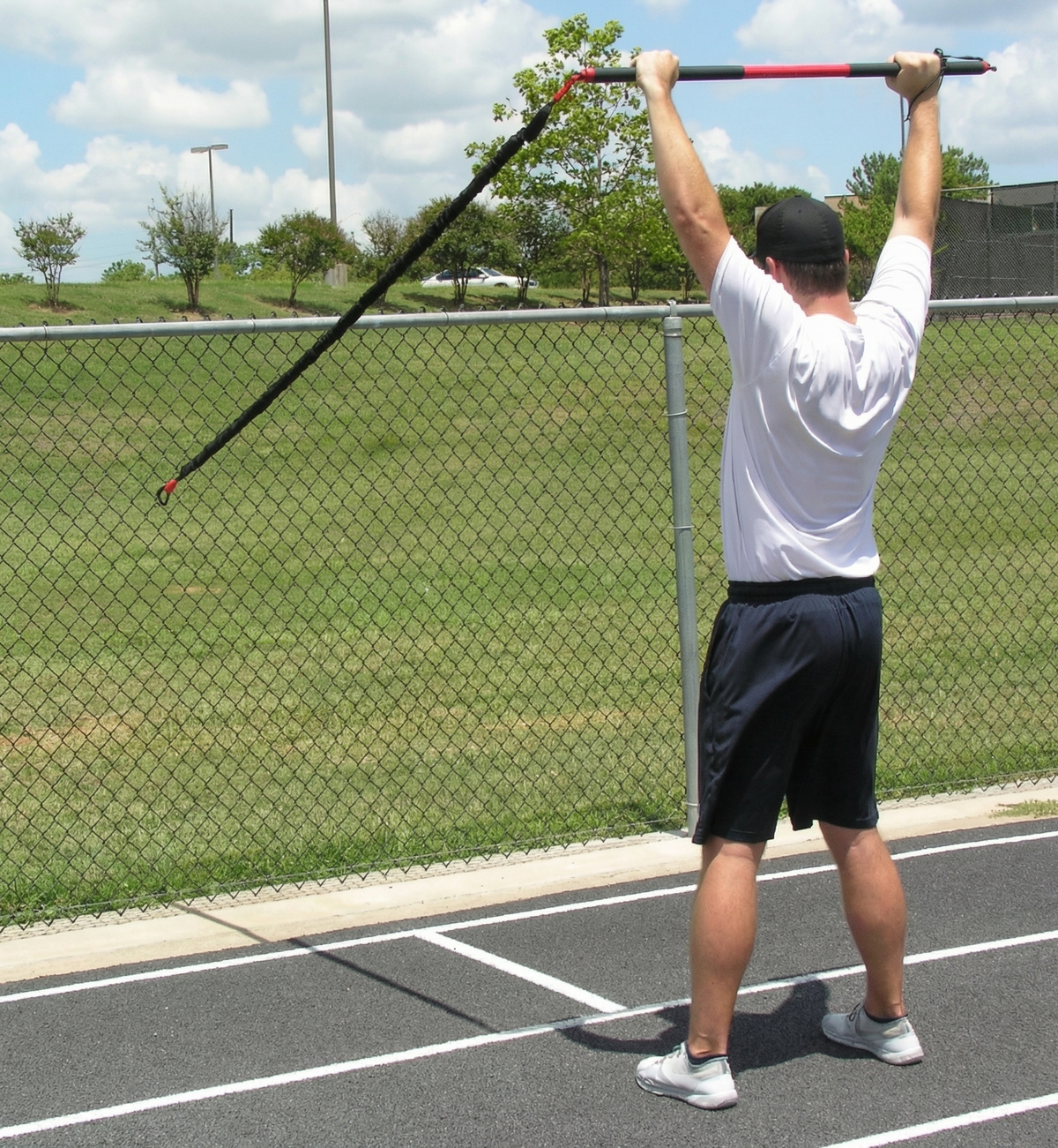 Athlete performing one-sided resisted arm raises with the KHAOS Pivoter, utilizing elastic rhythmic perturbations to drive scapular stabilization and kinetic chain organization for increased power.