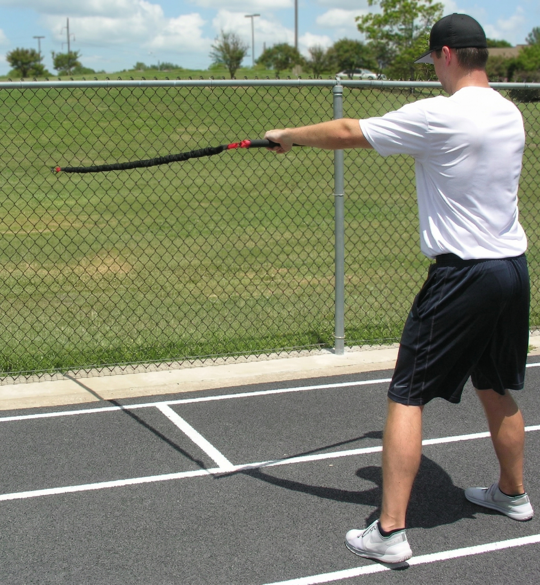 Athlete performing a one-sided resisted chest pull with the KHAOS Pivoter, utilizing elastic rhythmic perturbations to drive lead-side stabilization and kinetic chain organization for increased power.