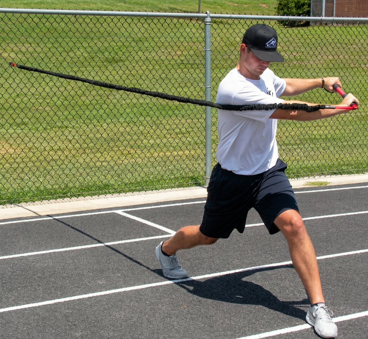Athlete performing a resisted trunk twist with the KHAOS Pivoter, utilizing elastic rhythmic perturbations to drive lead-side stabilization and kinetic chain organization for increased power.