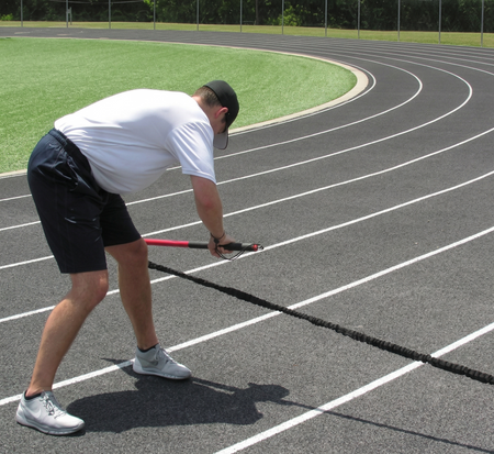 Athlete performing a bent-over row with the KHAOS Pivoter, utilizing elastic rhythmic perturbations to drive lead-side stabilization and kinetic chain organization for increased power.