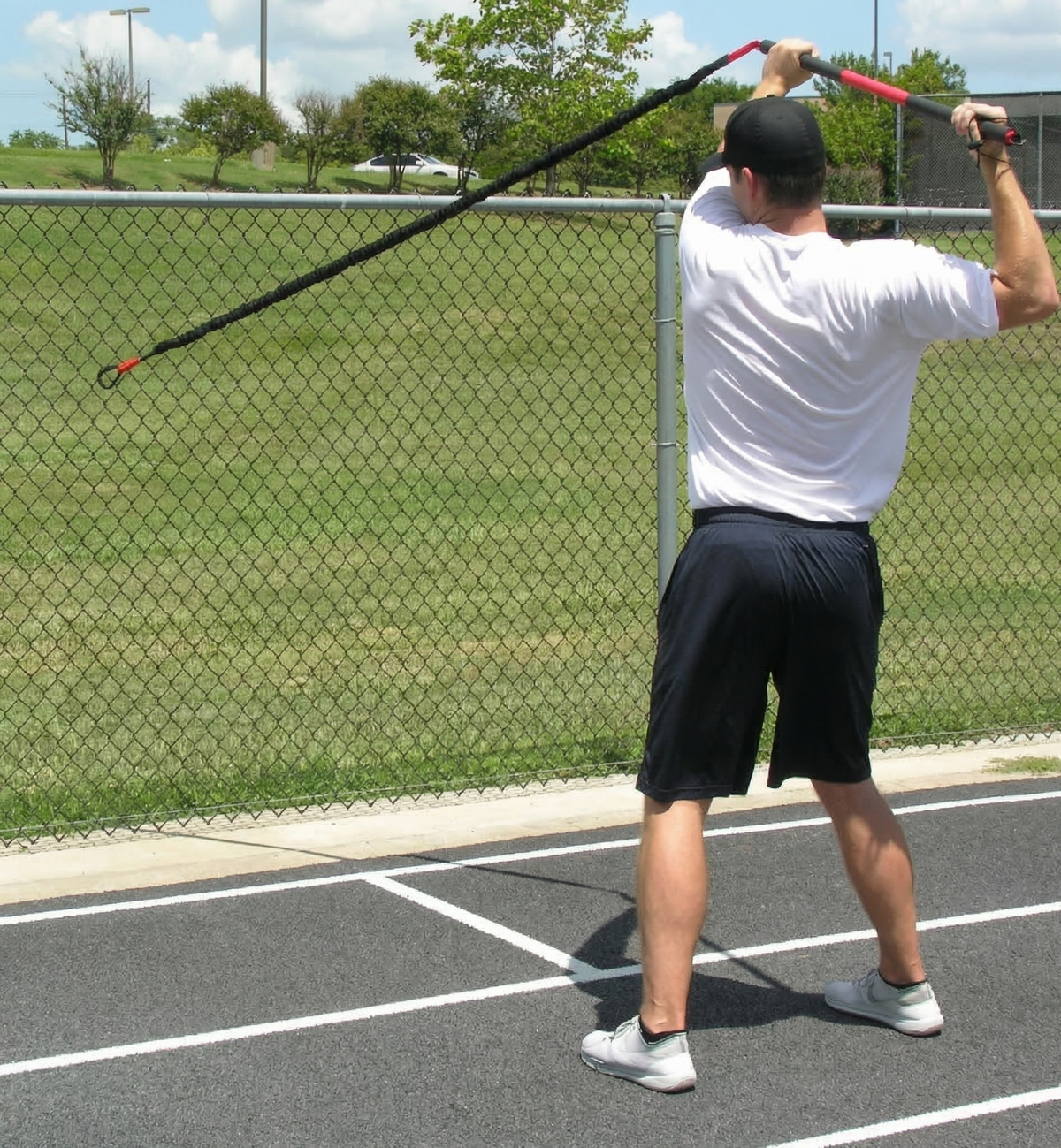 Athlete performing rear resisted rows with the KHAOS Pivoter, utilizing elastic rhythmic perturbations to drive lead-side stabilization and kinetic chain organization for increased power.