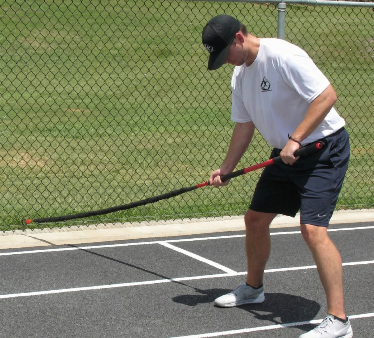 Athlete performing resisted trunk twists with the KHAOS Pivoter, utilizing elastic rhythmic perturbations to drive lead-side stabilization and kinetic chain organization for increased power.