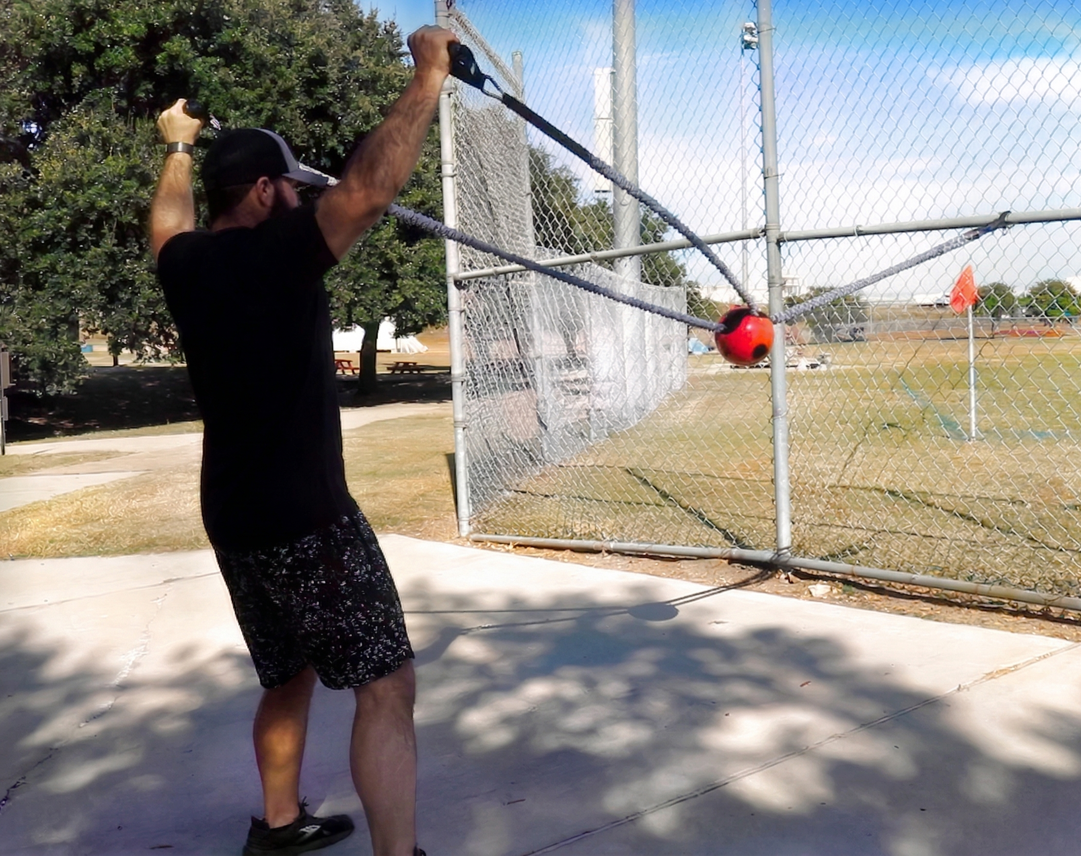 Athlete performing an overhead pull combining the sheathed tubing and Shoulder Shaker to drive scapular stabilization and kinetic chain organization via compound rhythmic perturbations.