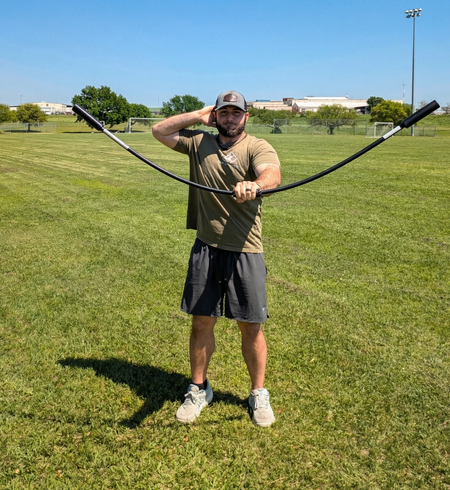 Athlete performing a front-facing rhythmic stabilization drill with the TAP® Shoulder Tube. Moving the device in a vertical plane with a pronated grip (palms down) creates oscillatory waves that drive scapular protraction and intensive anterior deltoid activation.