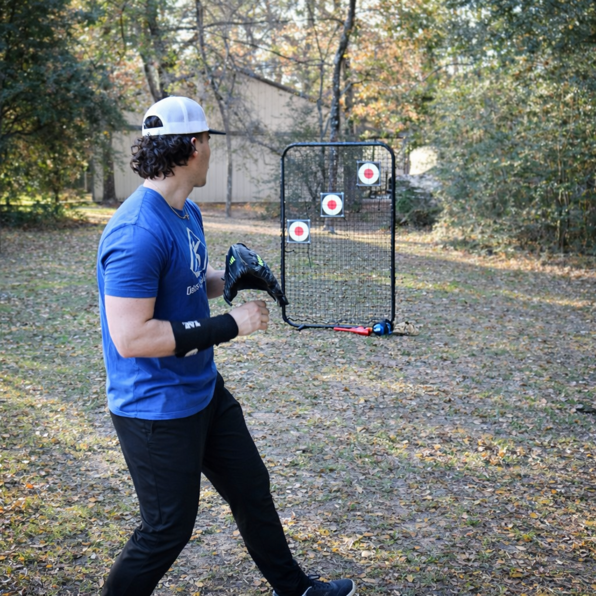 Baseball pitcher wearing the TAP® Weighted Forearm Sleeve with wrist positioned on forearm in the preparation phase before throwing, demonstrating proper sleeve placement for deceleration training.